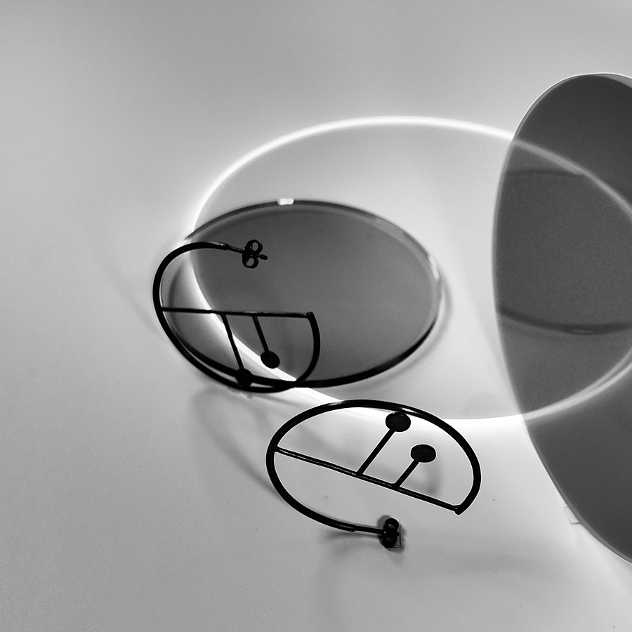 Black wire hoop earrings with a drawn line and dots, black and white photo