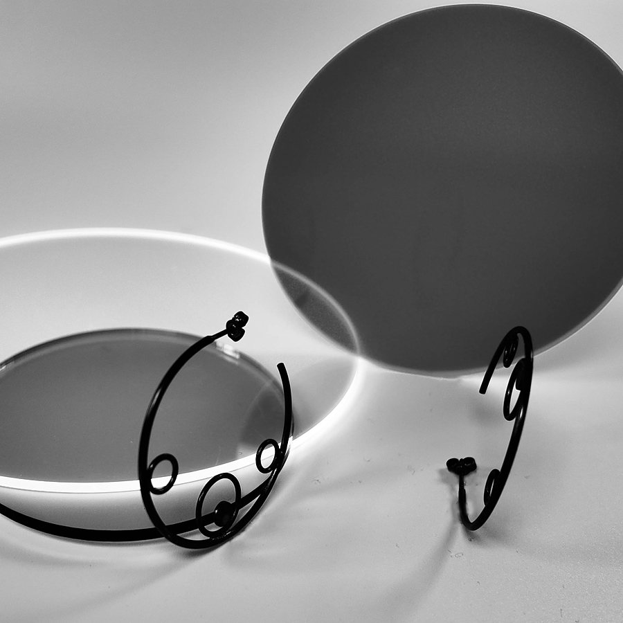 Black wire hoop earrings with small circles, beside acrylic discs