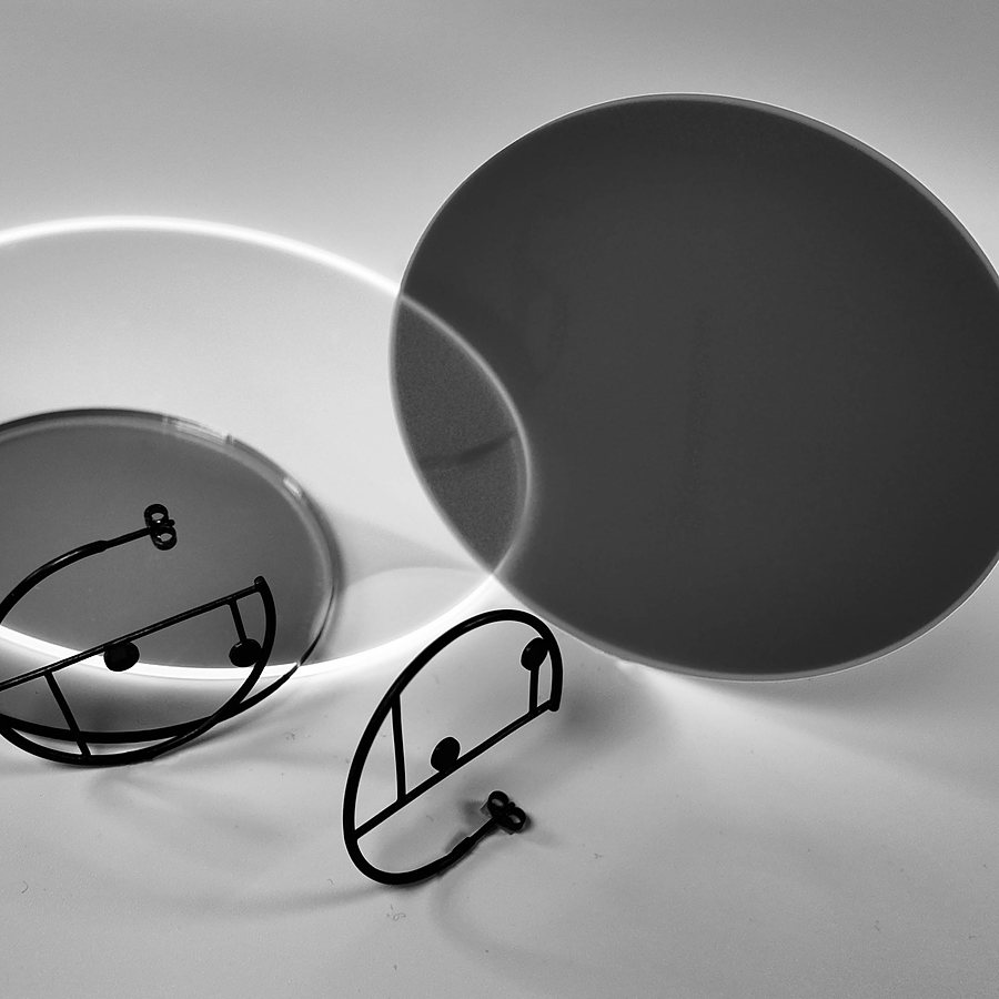 Black wire hoop earrings with two dots, near a dark acrylic disc