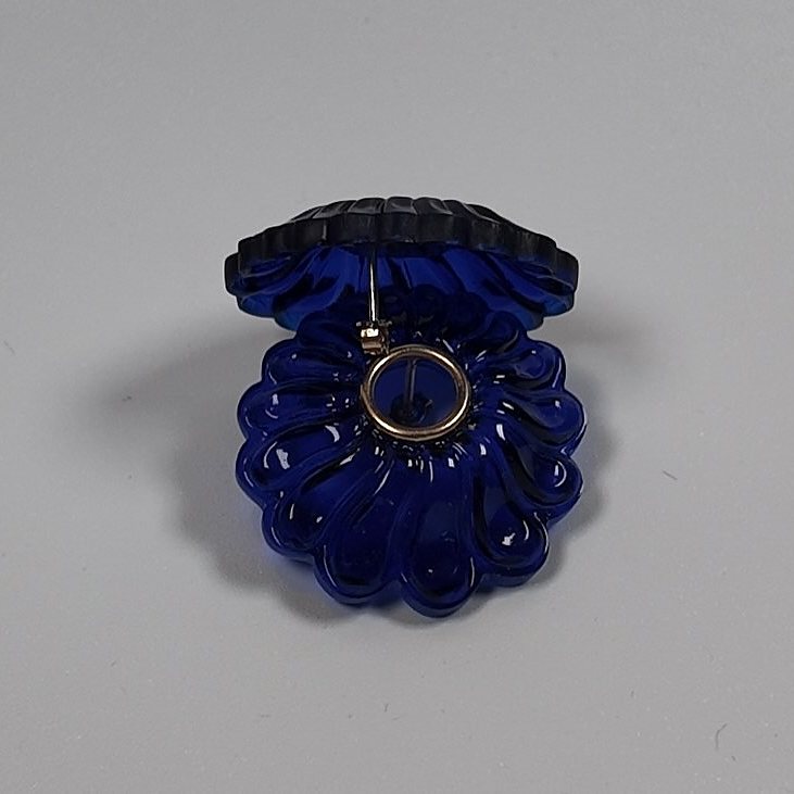 Close view of a dark blue acrylic flower-shaped stud earring with a gold-plated silver ring