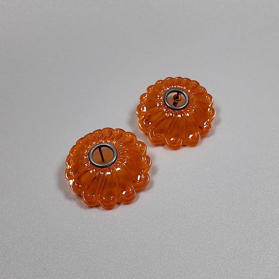 Orange acrylic flower-shaped stud earrings seen from another angle