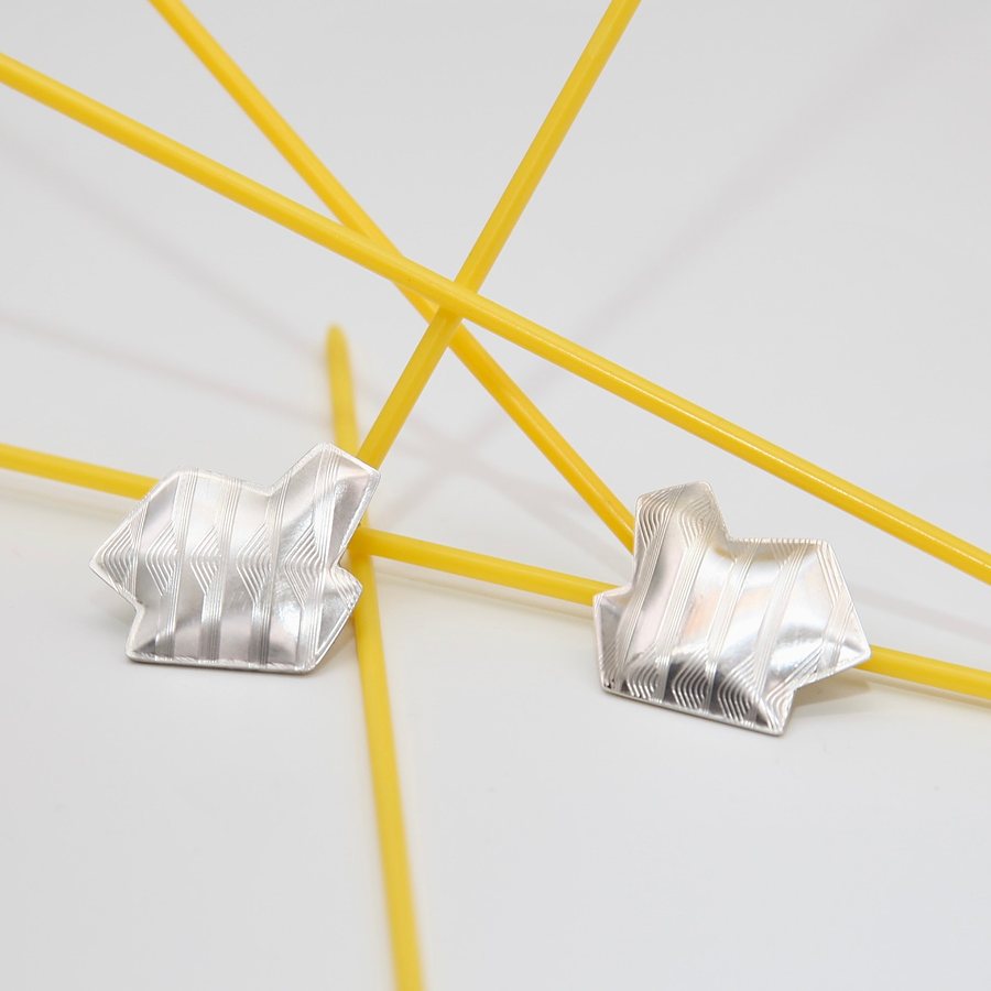 Pair of angular silver stud earrings with guilloché parallel lines, on yellow rods